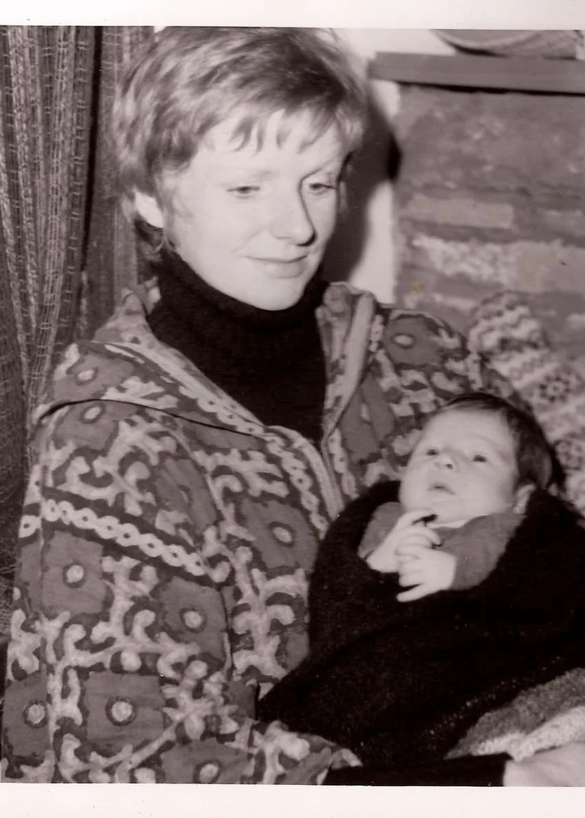 Black and white photo of a Gudrun Johnston's mom holding a newborn Gudrun indoors.